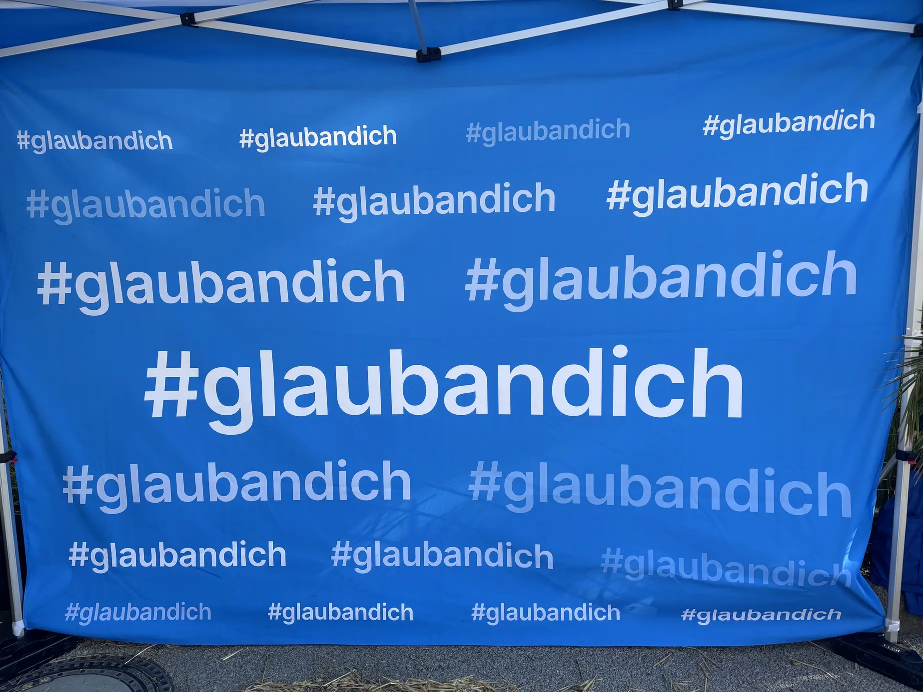 Blaue Zeltrückwand der Salzburger Sparkasse, vollflächig bedruckt mit dem Hashtag #glaubandich