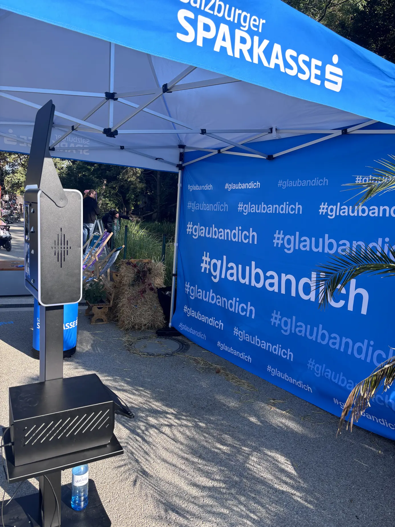 Seitenansicht der KI Fotobox mit Druckerstand unter dem blauen Zelt der Salzburger Sparkasse