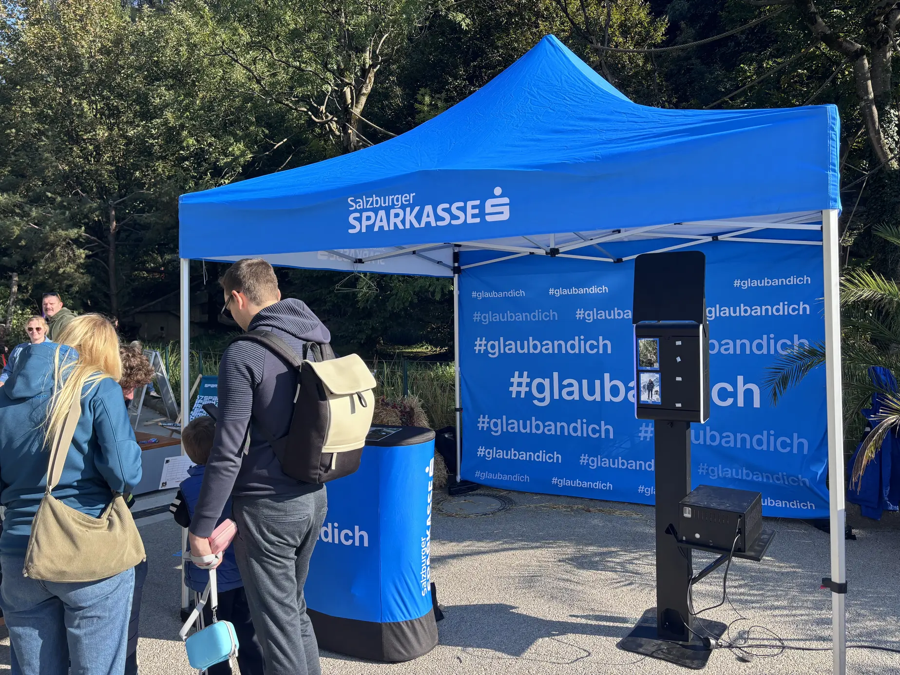 KI Fotobox von FiestaPics vor der #glaubandich-Rückwand im Zelt der Salzburger Sparkasse im Zoo Salzburg Hellbrunn