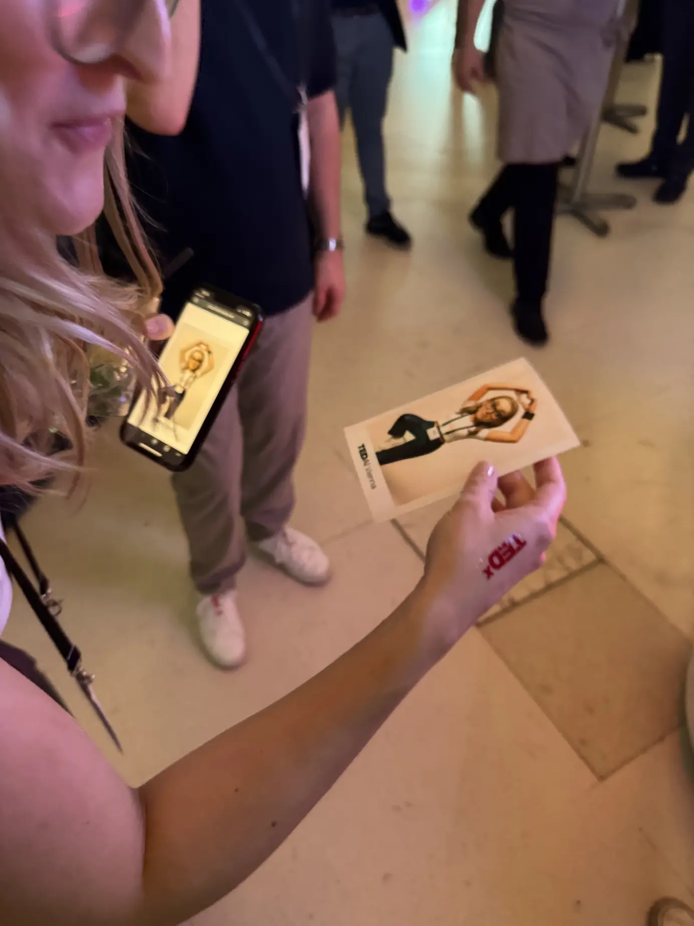 Gast hält den Sofortdruck seines KI-Porträts in der Hand und fotografiert ihn mit dem Handy