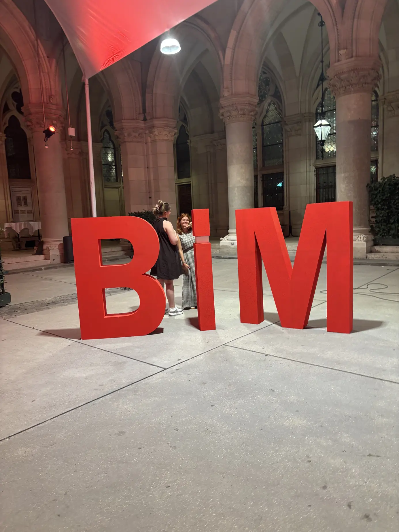 Gäste posieren zwischen den großen roten BIM-Buchstaben unter den Arkaden des Wiener Rathauses