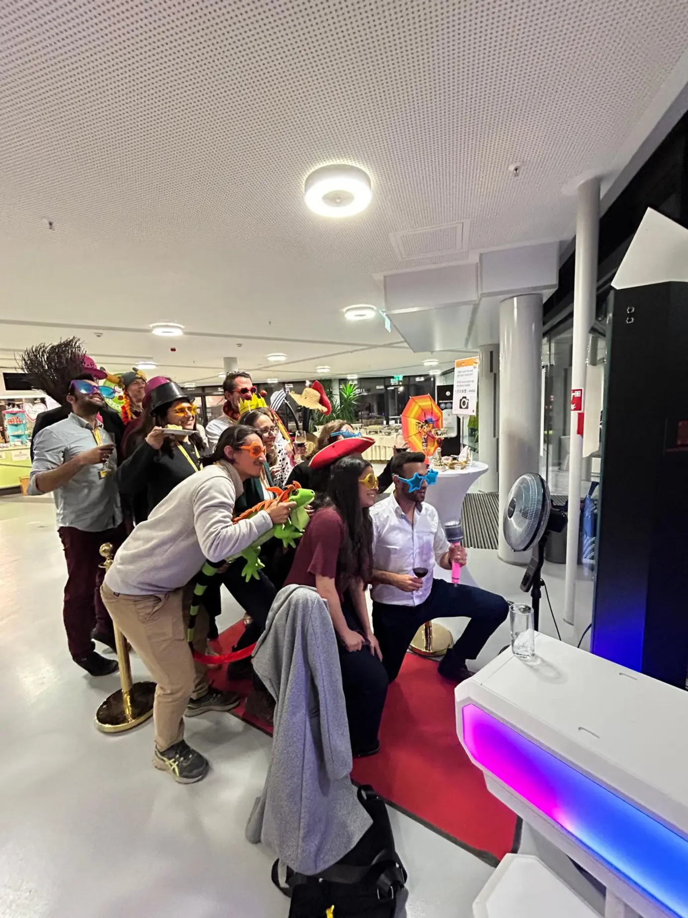 Große lachende Gruppe mit Requisiten vor dem Magic Mirror X im Foyer des welios Science Center Wels