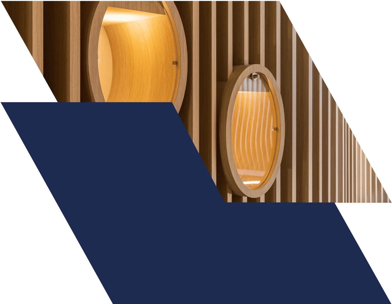 Agencement sur mesure en menuiserie bois : cabines ovales en bois clair éclairées de l'intérieur, intégrées dans une cloison en tasseaux verticaux.