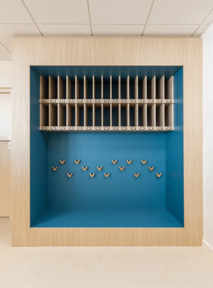 Mobilier et agencement bois sur mesure : niche murale en bois clair à fond bleu, casiers de tri courrier et patères en bois.
