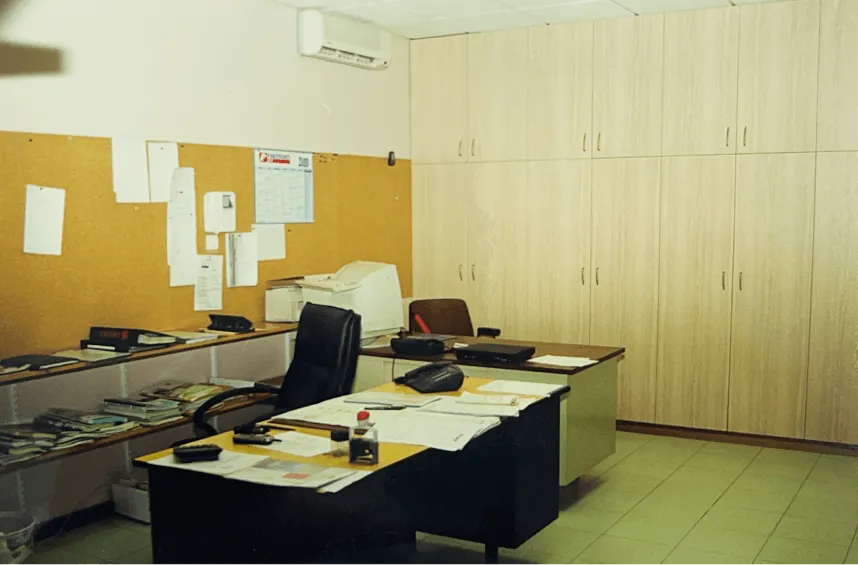 Agencement intérieur bois sur mesure : bureau d'entreprise équipé de rangements en bois sur mesure, fauteuil noir et documents posés sur la table de travail.