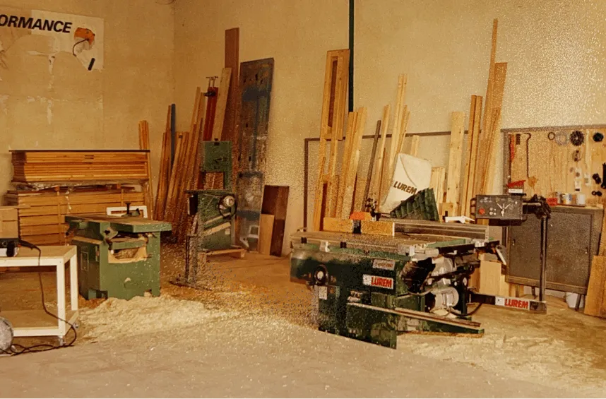 Atelier de menuiserie : intérieur équipé de machines à bois, planches empilées et sciure au sol, dans l'atelier de menuiserie de Montpellier.