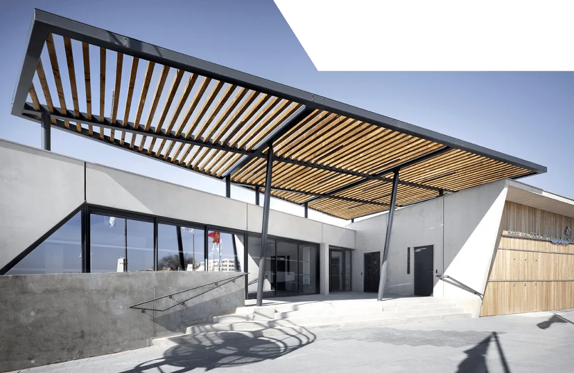 Menuiserie extérieure et bardage bois sur mesure : bâtiment contemporain avec auvent en lattes de bois sur structure métallique, façade béton et baies vitrées noires.