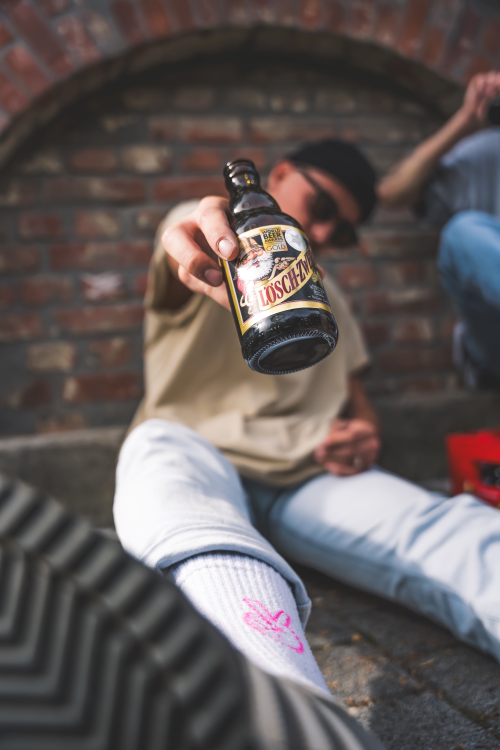 Ein junger Mann mit Cap hält lässig eine Lösch-Zwerg-Flasche in die Kamera.