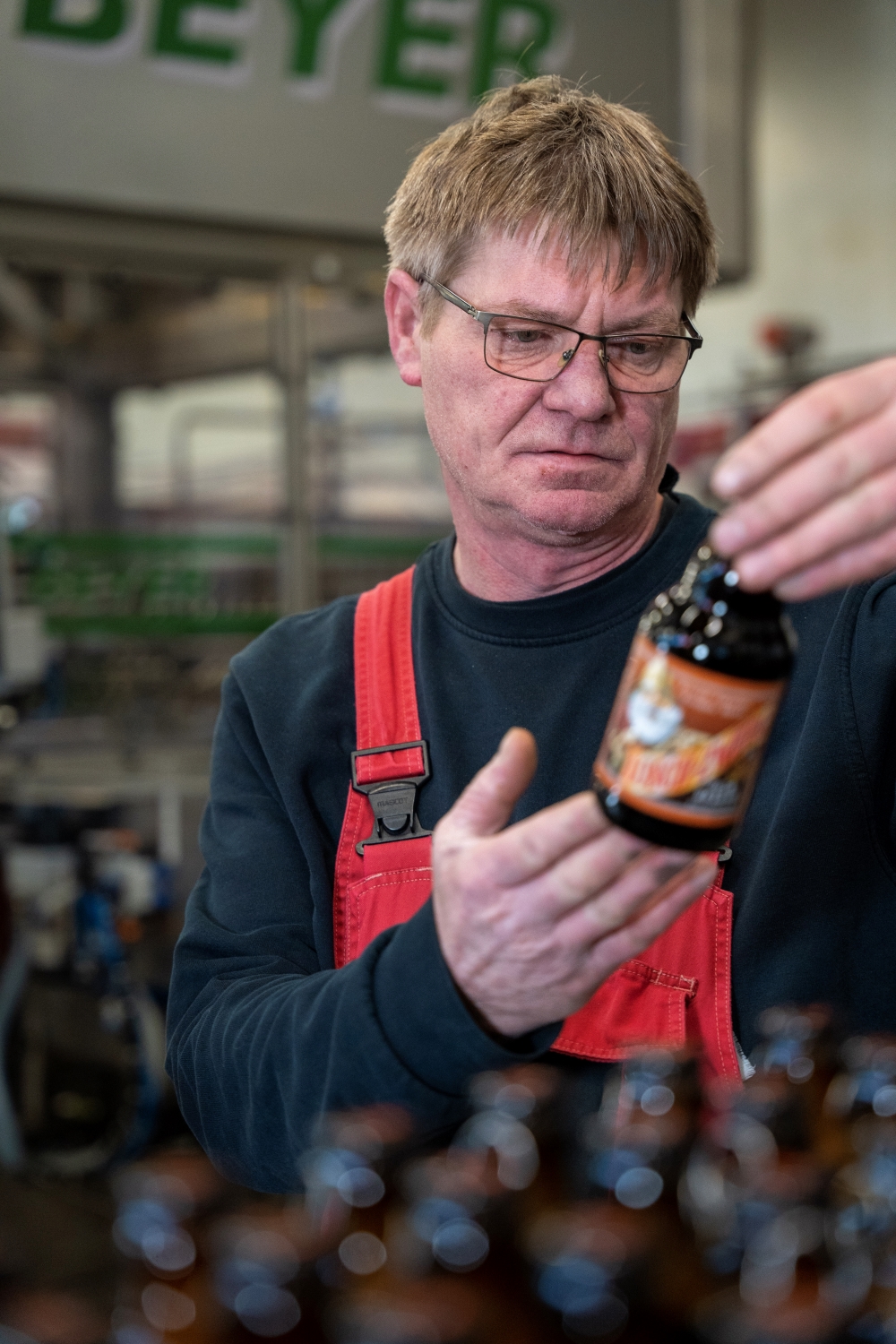 Ein Mitarbeiter begutachtet eine Lösch-Zwerg-Flasche.