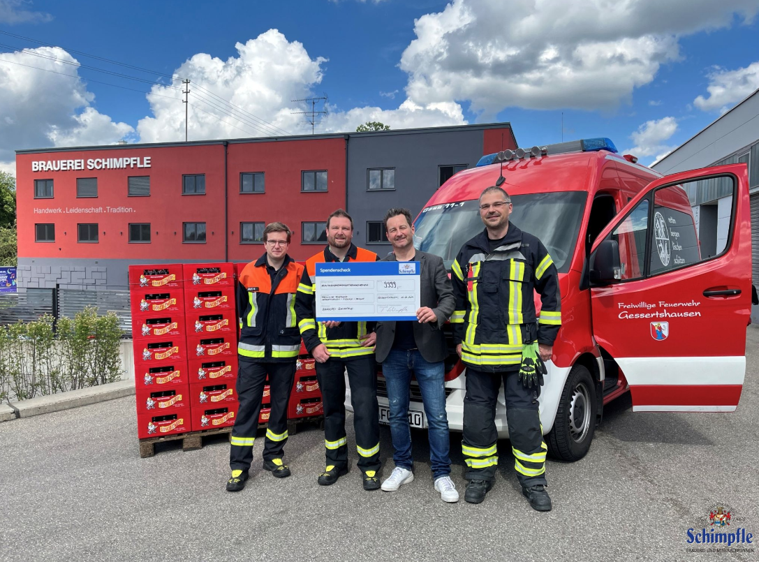 Thomas Schimpfle überreicht Feuerwehrleuten einen Scheck.