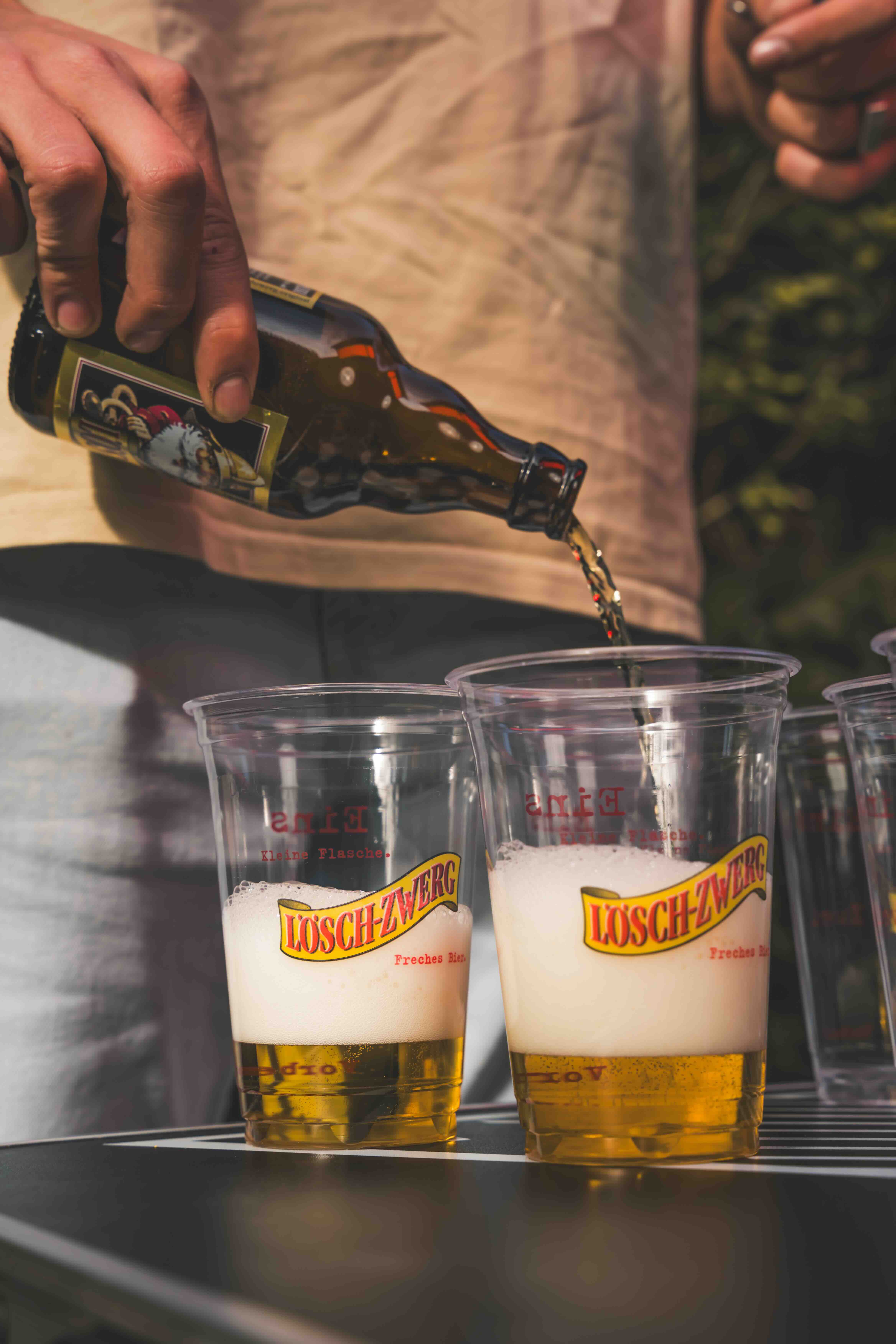 Jemand schenkt Bier in Lösch-Zwerg-Becher.