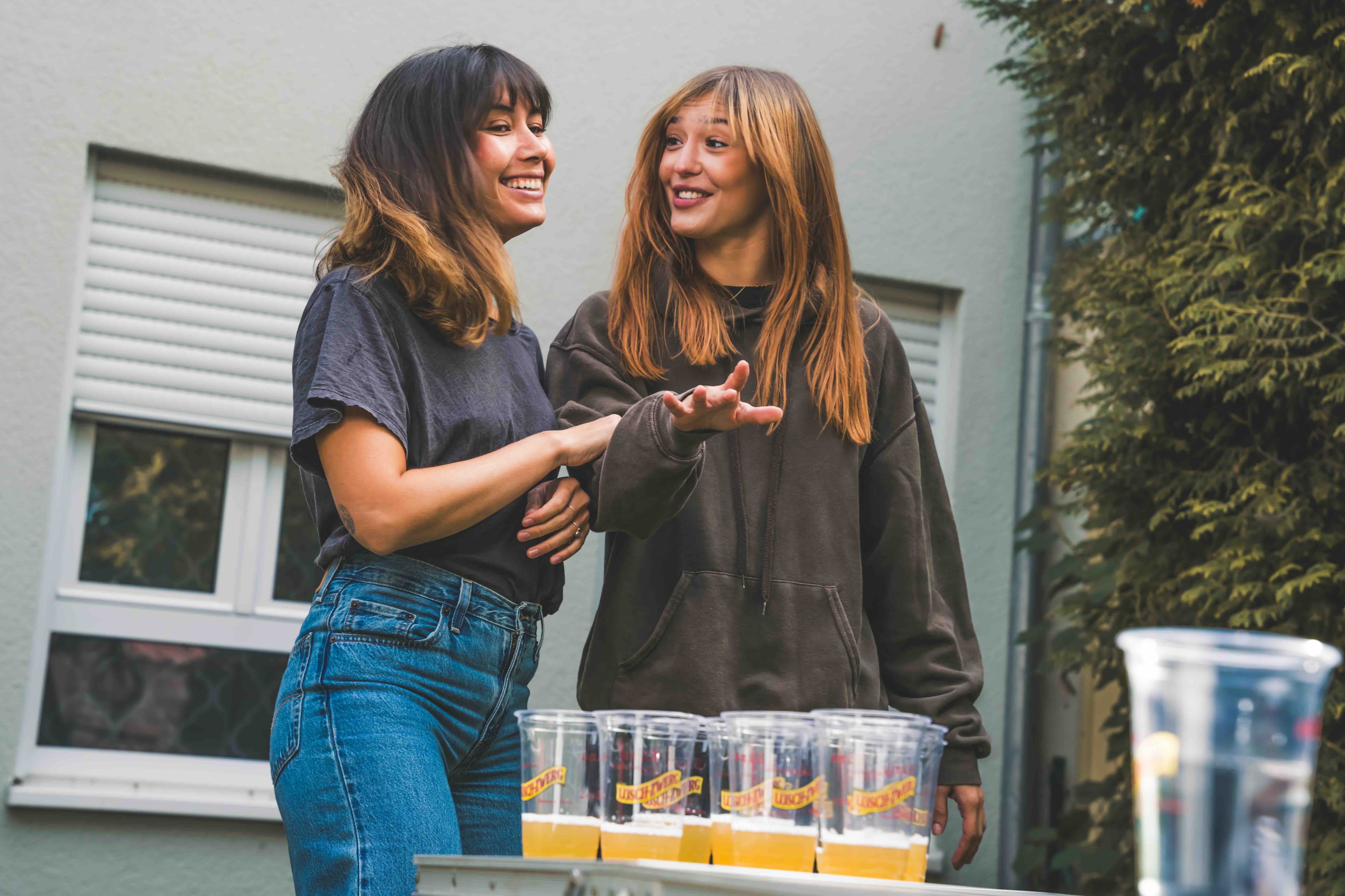 Zwei Frauen stehen nebeneinander vor einem Bierpong-Tisch.