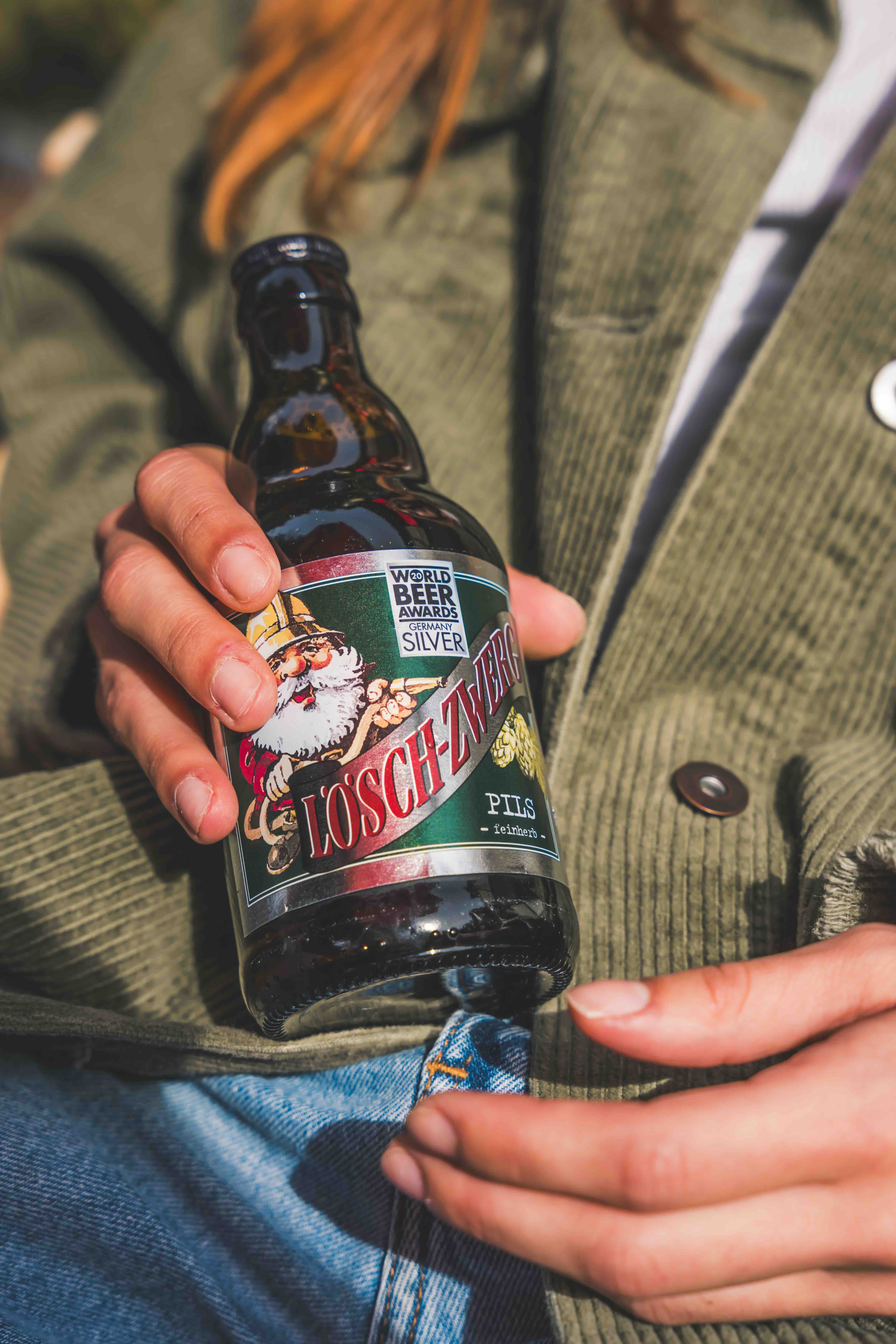 Jemand hält eine Lösch-Zwerg Pils Flasche.