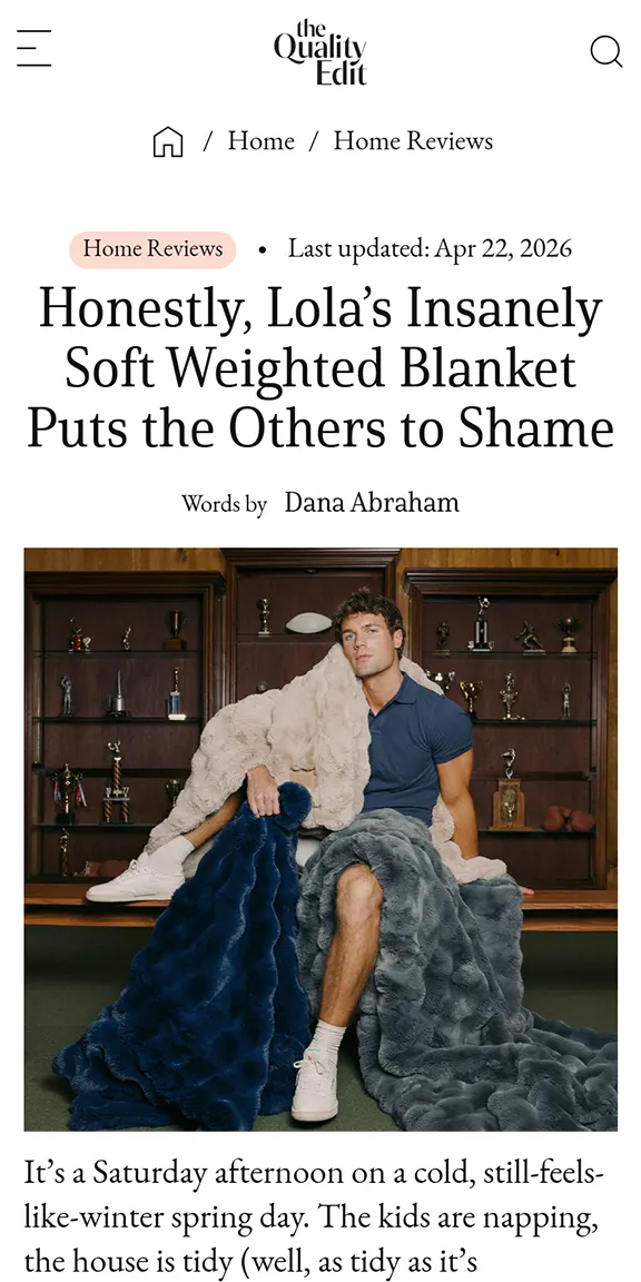 Man sitting on bench wrapped in three soft, plush weighted blankets in beige, navy, and gray.