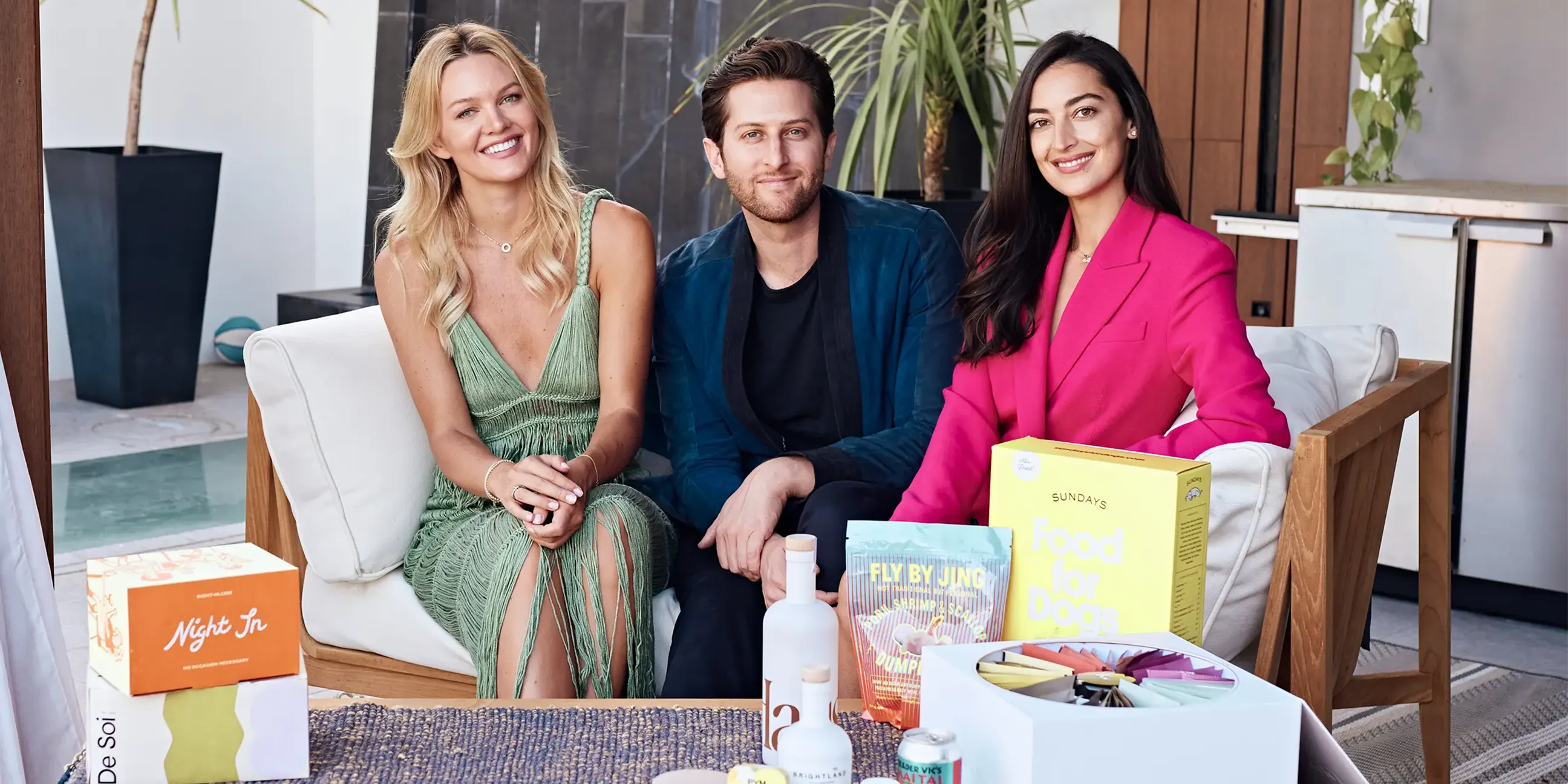 ThQuality Media founders seated on a couch behind a table with assorted food and drink products.