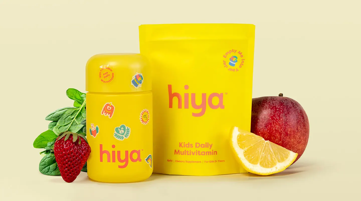 Yellow Hiya kids daily multivitamin bottle and refill pack with strawberry, spinach, lemon, and apple.