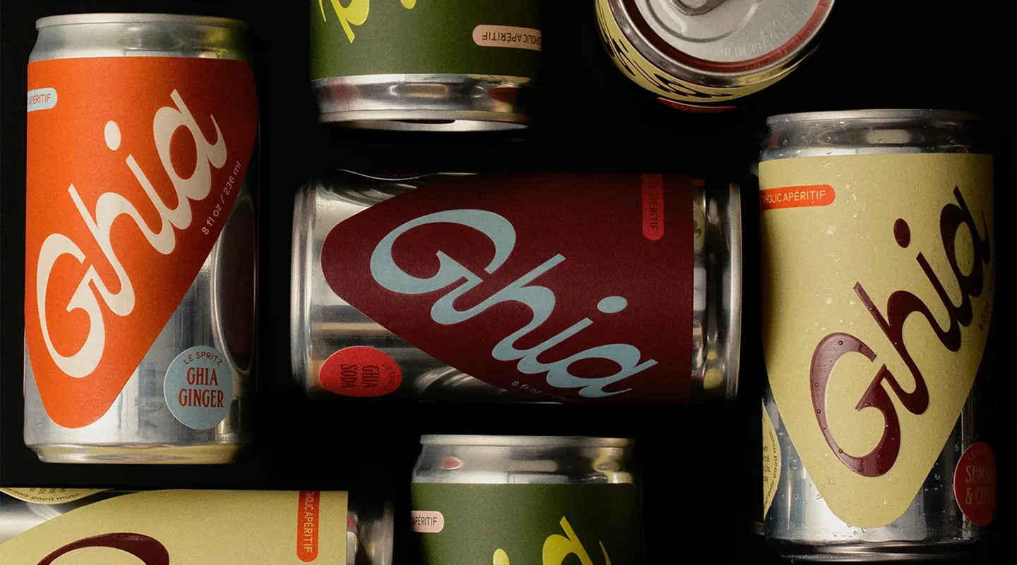 Several colorful Ghia non-alcoholic aperitif cans arranged on a dark surface.