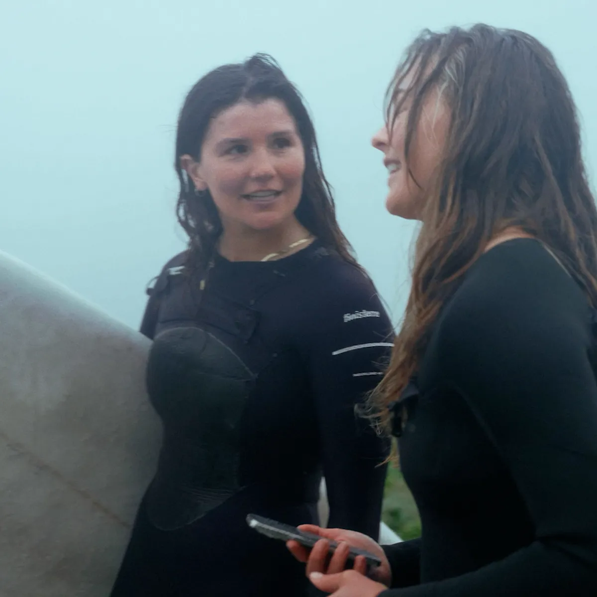 Two surfers in wetsuits