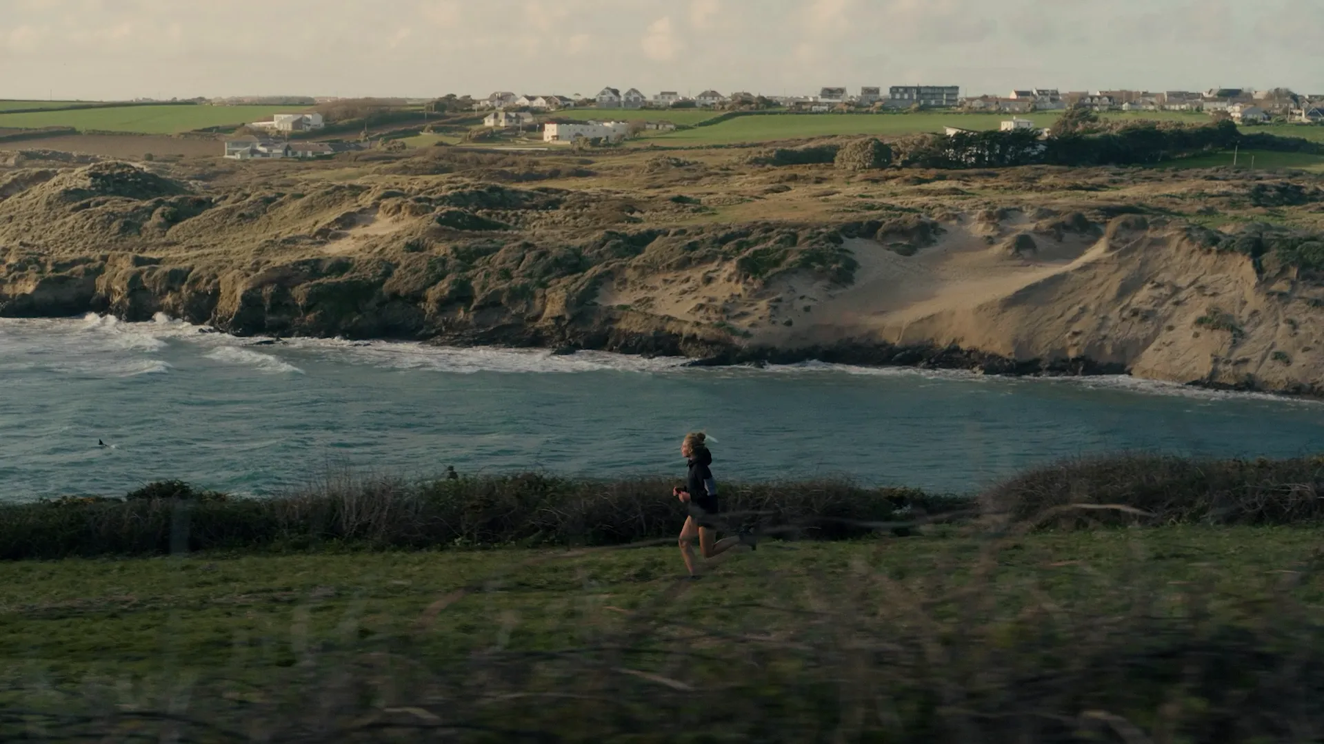 Woman running on a cliff above a beach