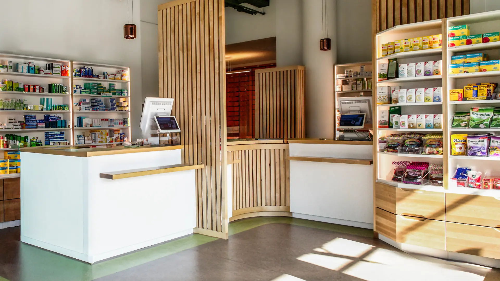 Der Innenraum der Apotheke am Goetheplatz. Links und in der Mitte befinden sich jeweils eine Theke mit Kasse. Rechts und im Hintergrund stehen Regale mit Medikamenten, Tees und Husten-Bon-Bons.