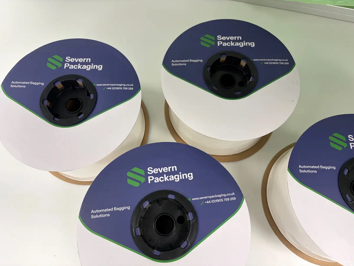 Four rolls of packaging film labeled Severn Packaging Automated Bagging Solutions on white surface.