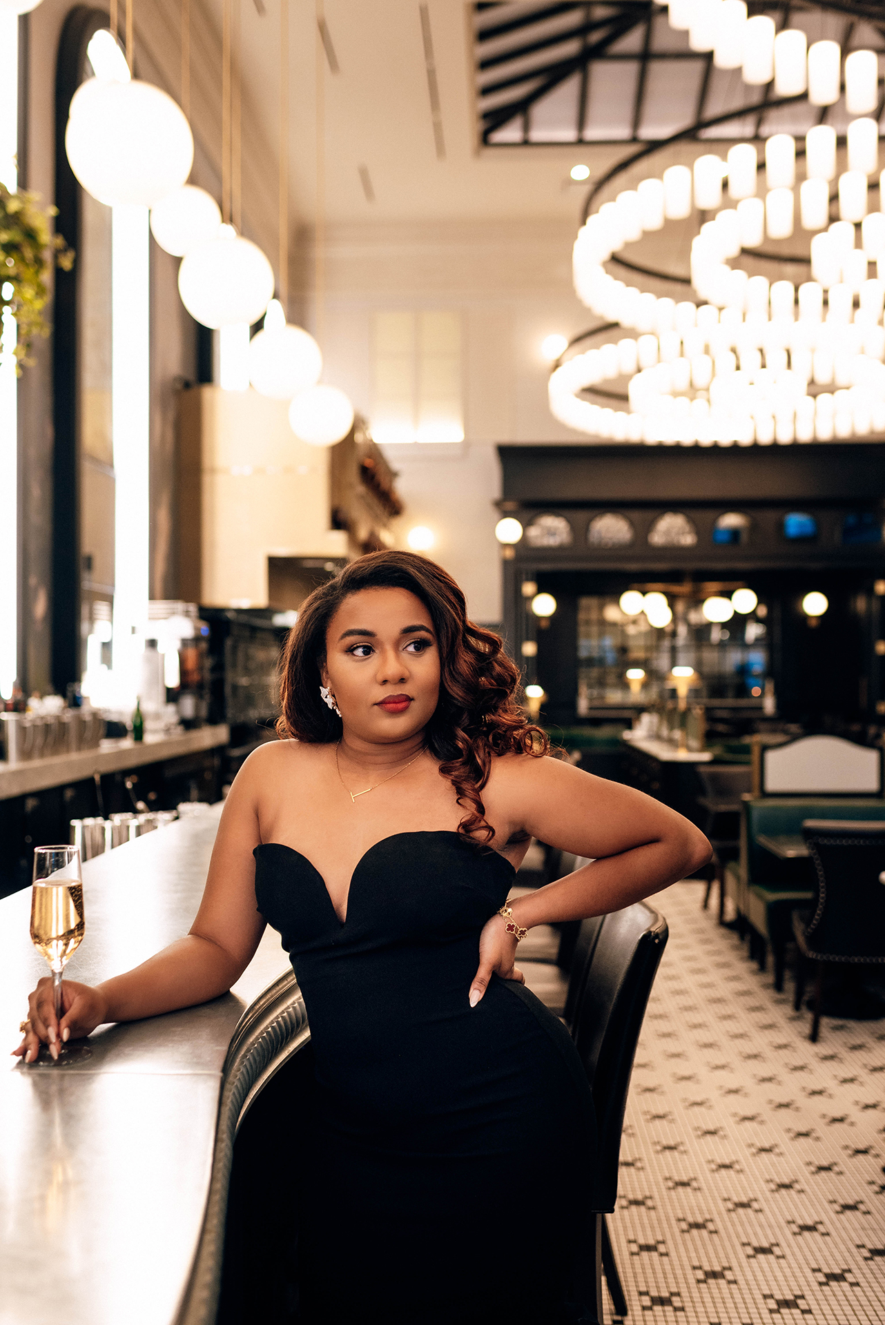 Jacinda Merchant owner of J'Adore Bridal, branding portraits at La Belle Helene in Charlotte, NC. Holding a glass of champagne leaning against the bar. 