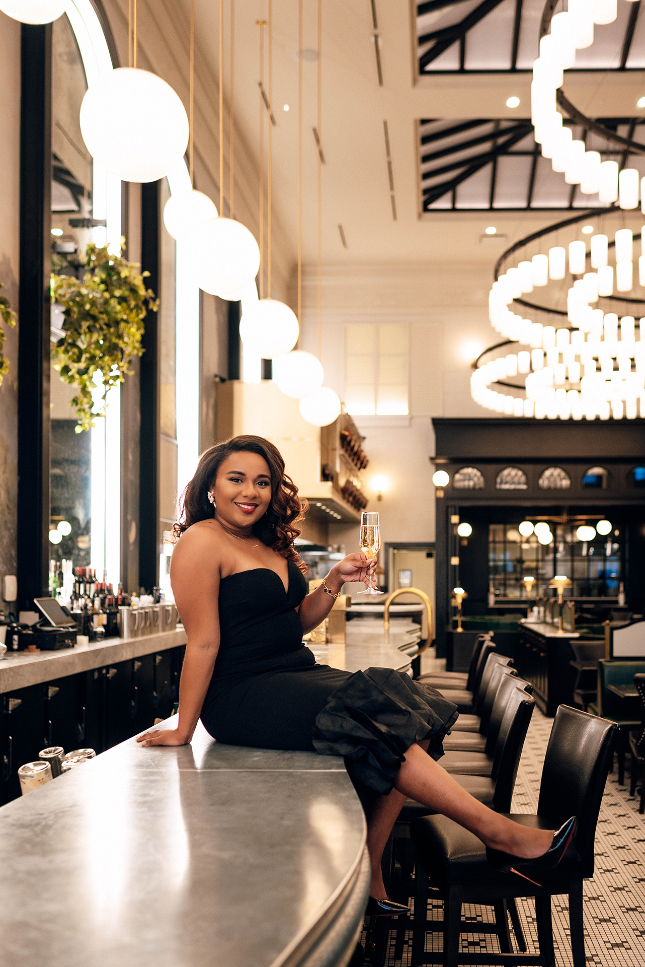 Jacinda Merchant owner of J'Adore Bridal, branding portraits at La Belle Helene in Charlotte, NC. Holding a glass of champagne sitting on top of bar.