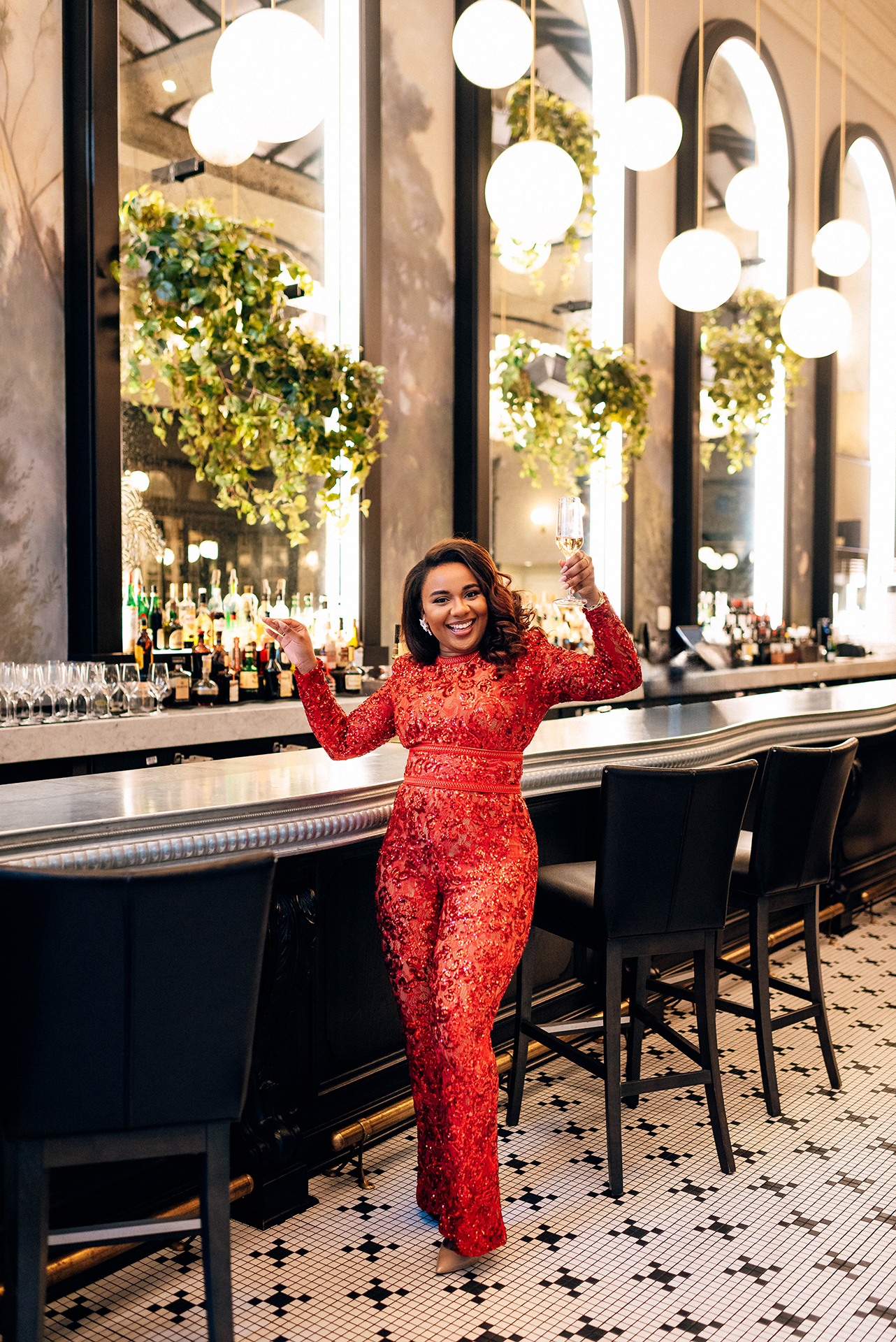 Jacinda Merchant owner of J'Adore Bridal, branding portraits at La Belle Helene in Charlotte, NC. Holding a glass of champagne dancing near the bar. 