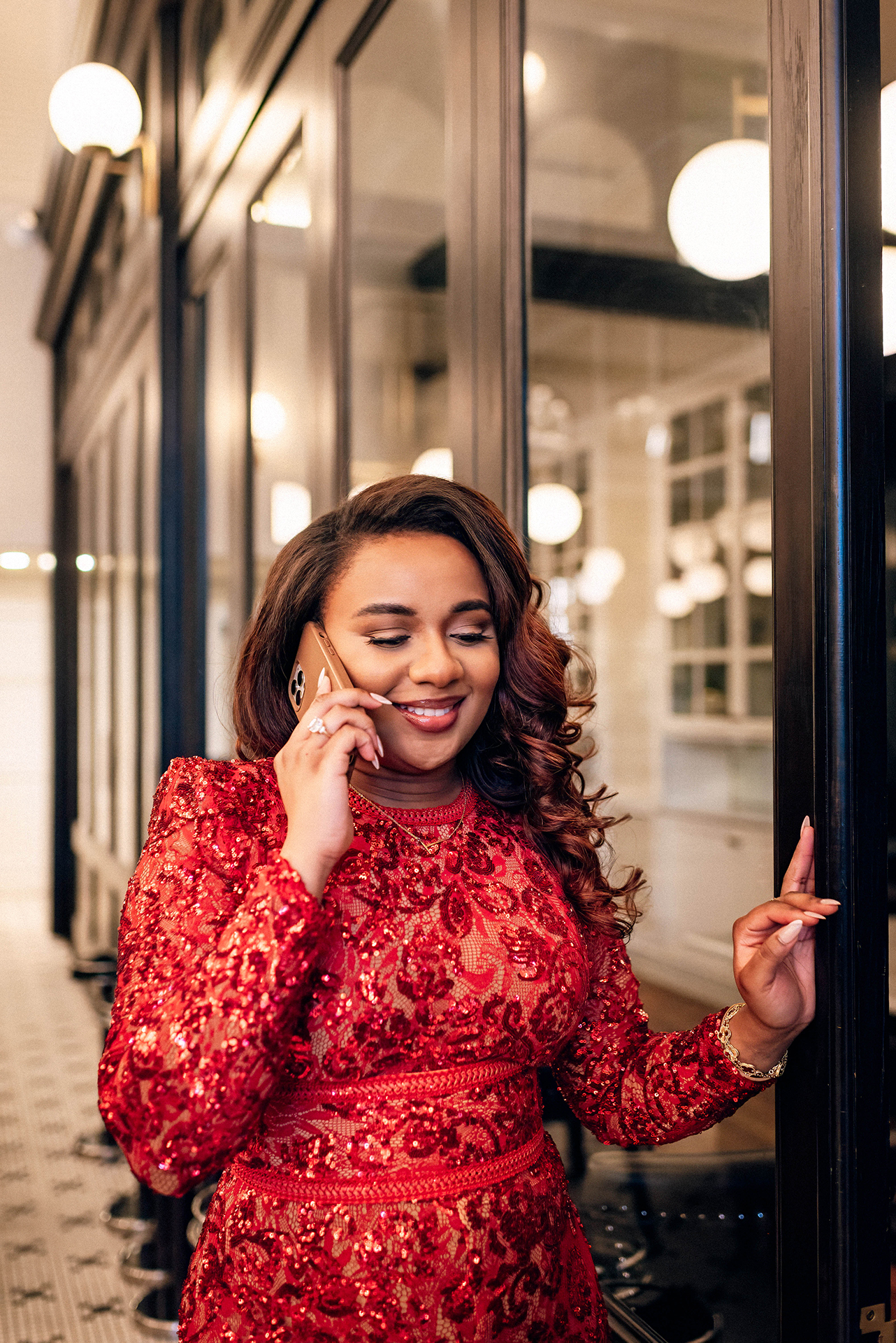 Jacinda Merchant owner of J'Adore Bridal, branding portraits at La Belle Helene in Charlotte, NC. Talking on phone leaning against the wall of closed booth area.