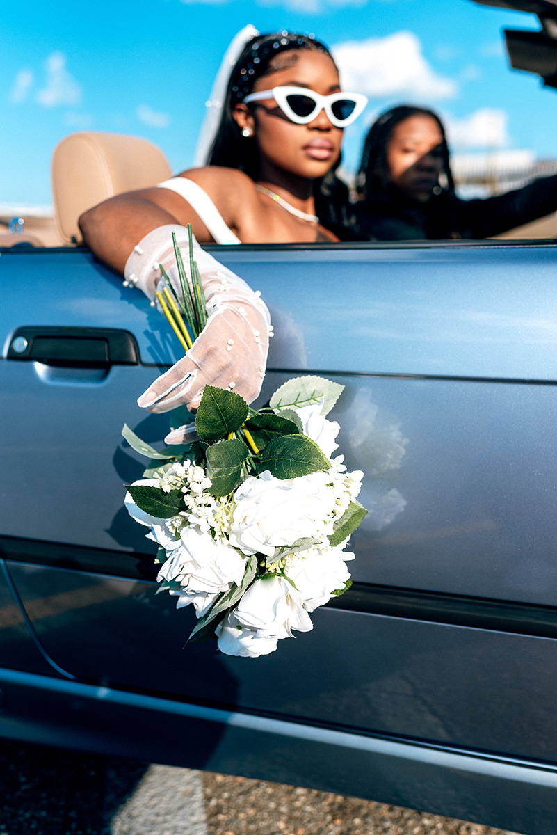 Elopement styled shoot in Camp North End Charlotte, NC with same-sex couple in classic convertible. Bride in passenger seat with bouquet hanging over door outside of car