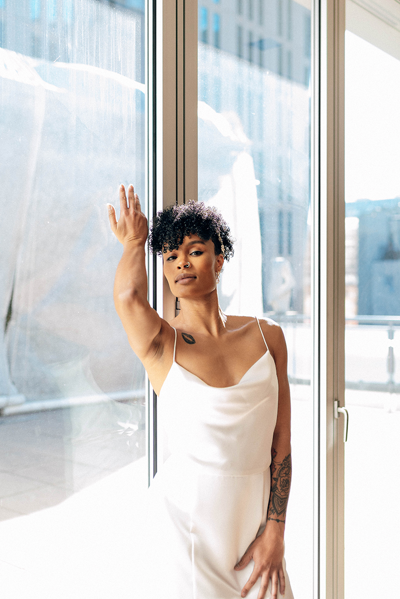 Wedding styled shoot at 220 North Tryon in Charlotte, NC and Foundation of the Carolinas art gallery. One bride leaning against floor to ceiling windows