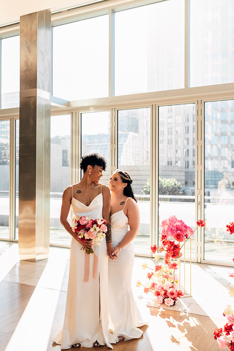 Wedding styled shoot at 220 North Tryon in Charlotte, NC and Foundation of the Carolinas art gallery. Couple standing by alter with pink flowers holding hands. 