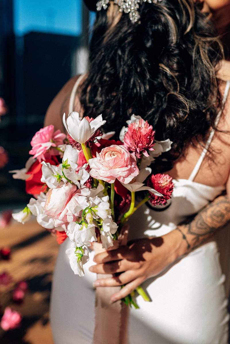 Wedding styled shoot at 220 North Tryon in Charlotte, NC and Foundation of the Carolinas art gallery. couple hugging, one partner holding bouquet behind other's back