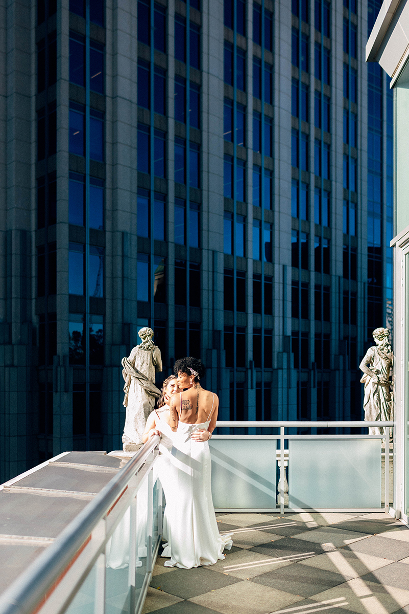 Wedding styled shoot at 220 North Tryon in Charlotte, NC and Foundation of the Carolinas art gallery. Couple standing on balcony of top floor in front of charlotte cityscape 