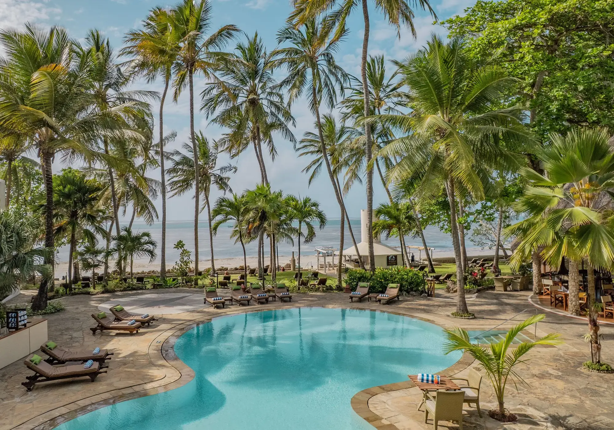 Pool surrounded by palm trees with the Indian Ocean behind at Severin Sea Lodge
