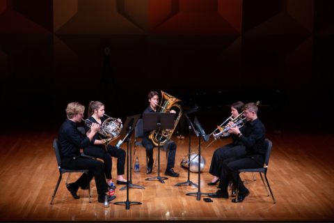 A brass quintet performing on stage