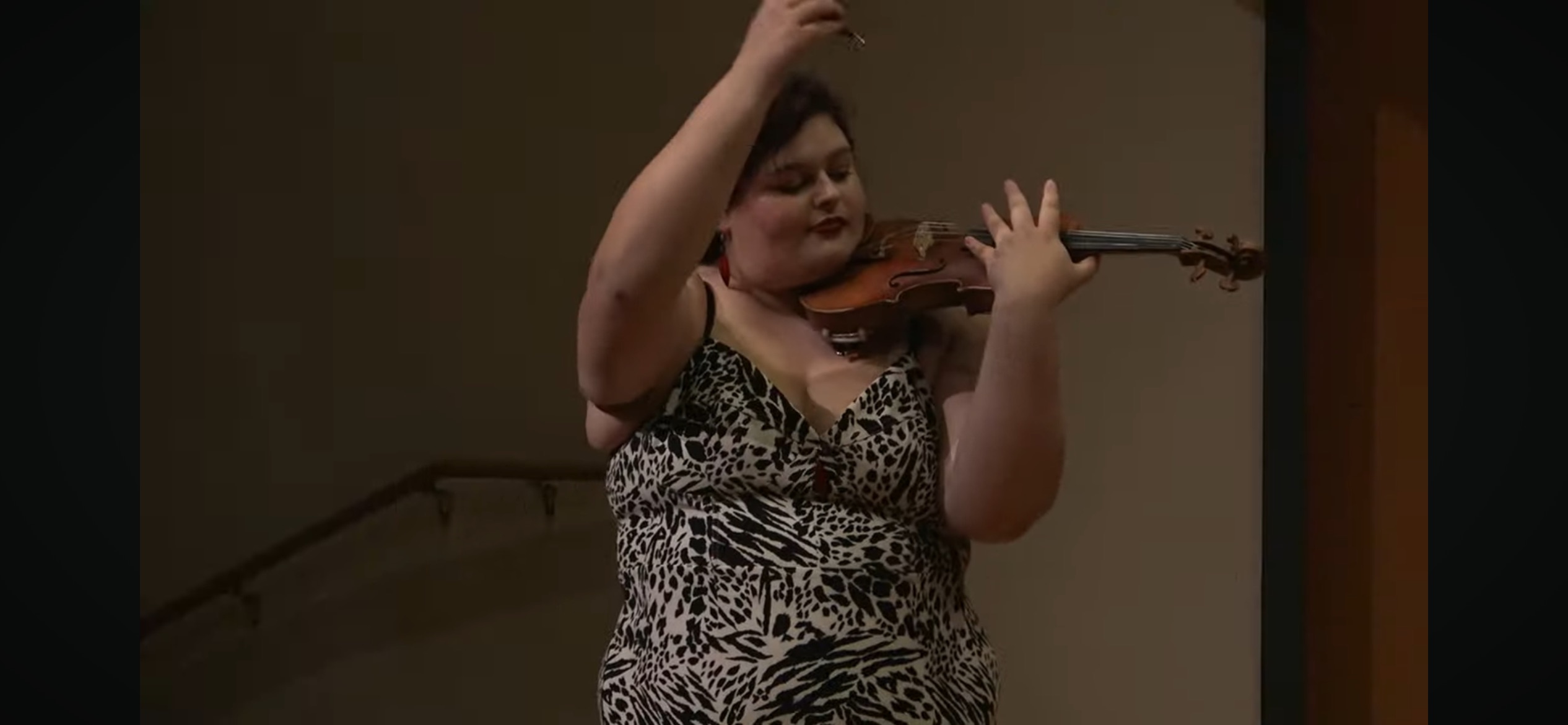 Georgia in an animal print dress playing her violin.