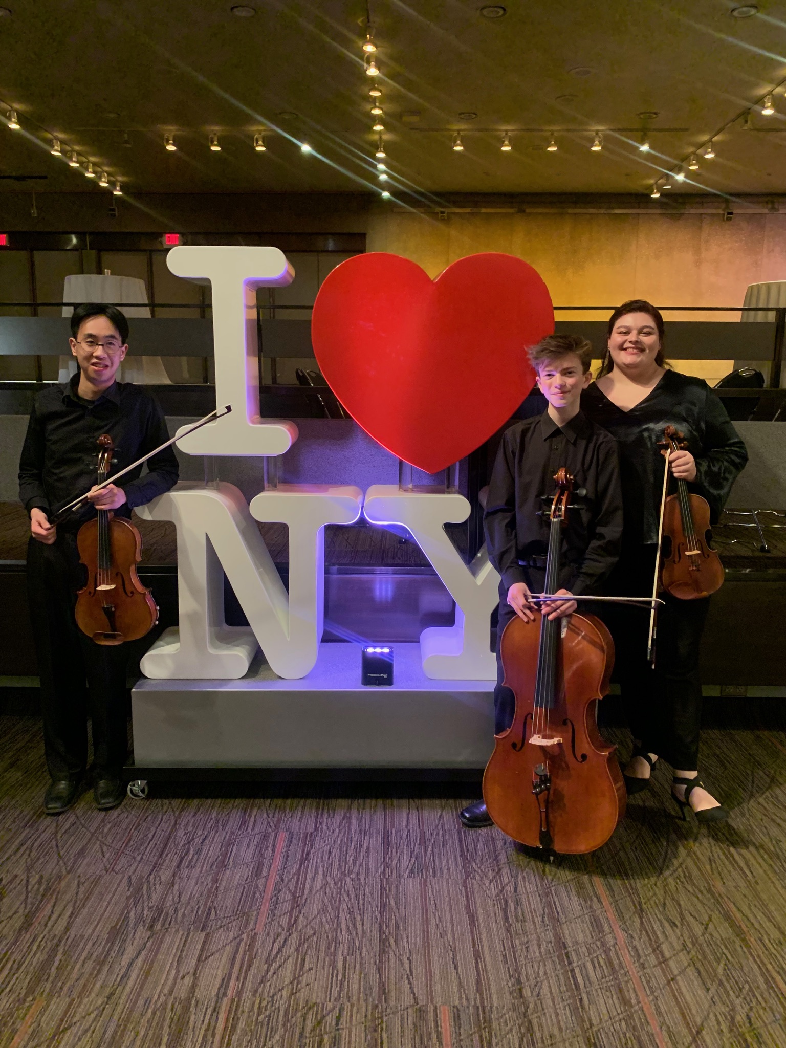 Georgia and her trio standing with an "I heart NY" sign after playing for the reception of the NY State of the State address.