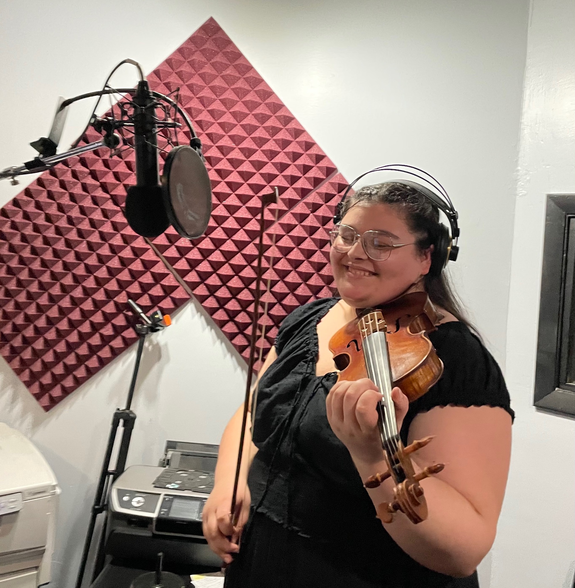 Georgia smiling in a recording booth with her violin.