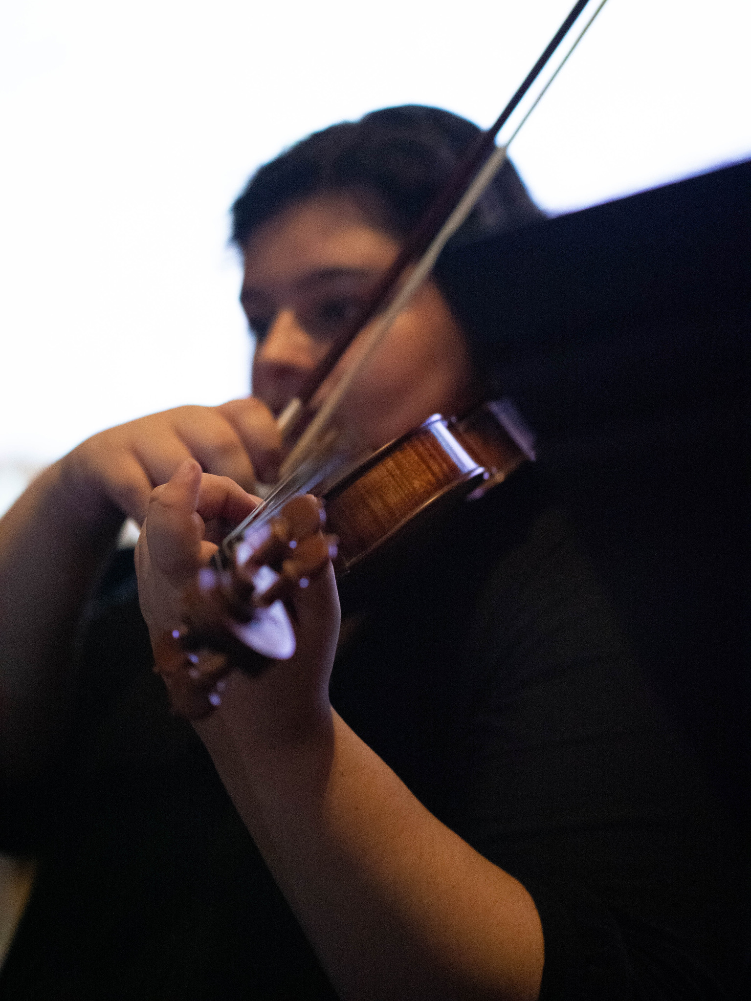 Georgia playing her violin with her face out of focus and her hand on focus.