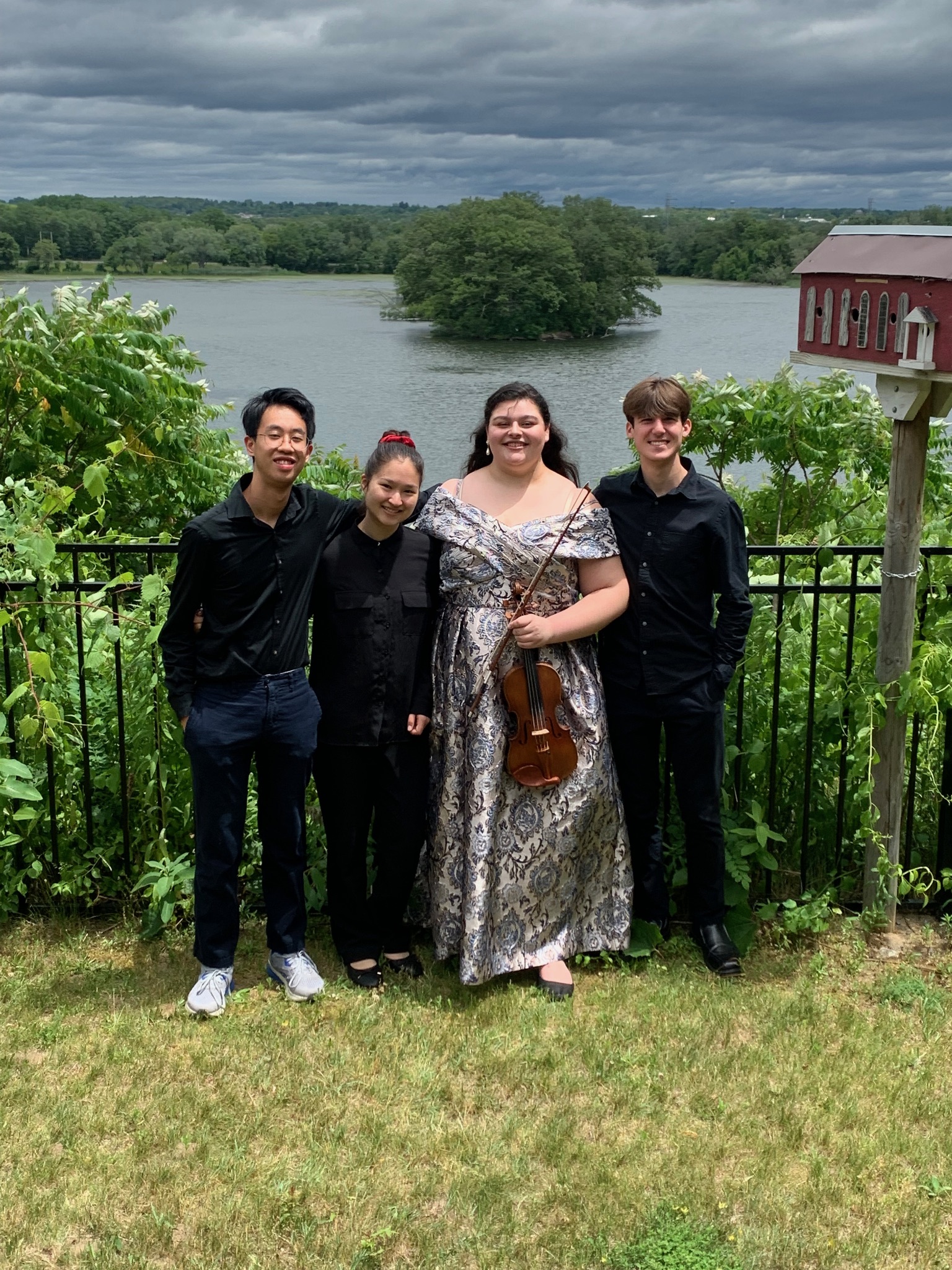 Georgia in her senior recital dress with her string quartet in front of a lake.
