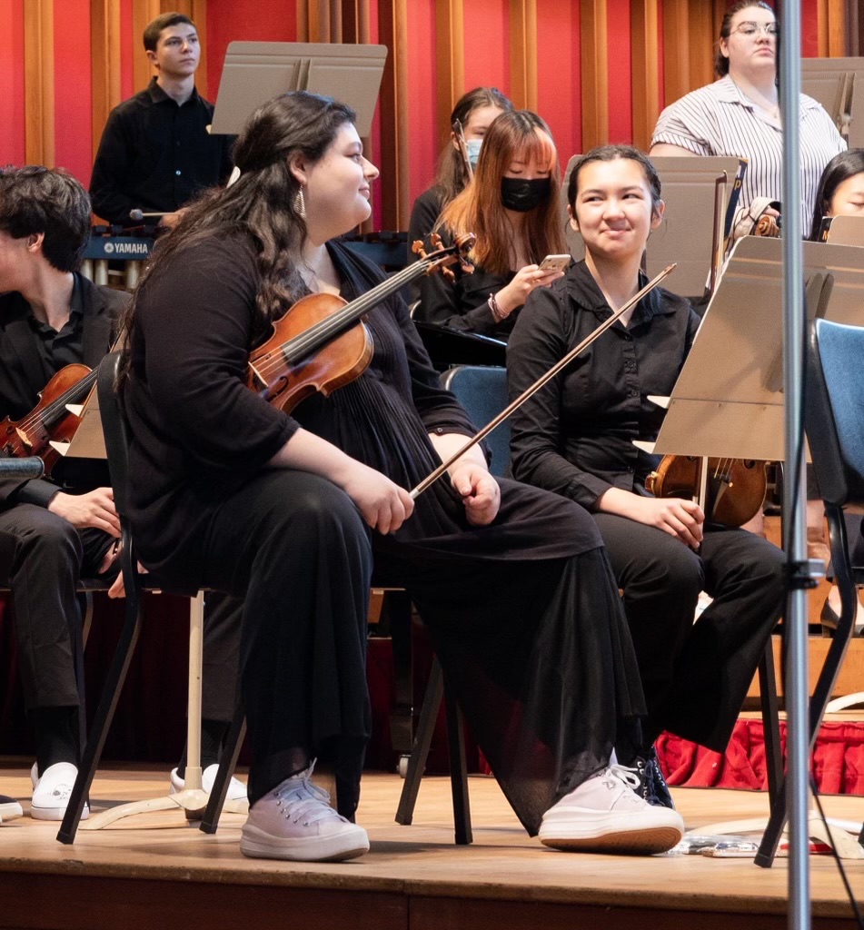Georgia and her friend, Caitlin, sitting in orchestra.