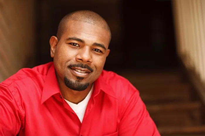 An image of a confident man in a red shirt smiling calmly on stairs — discover why understanding yourself is crucial for personal growth and mental well-being.