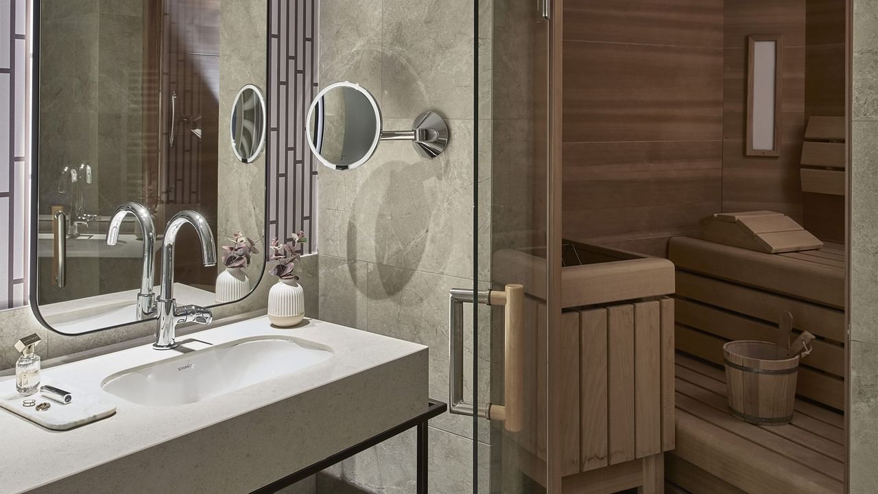 Banheiro com pia, espelho e sauna na Carnica SPA Suite