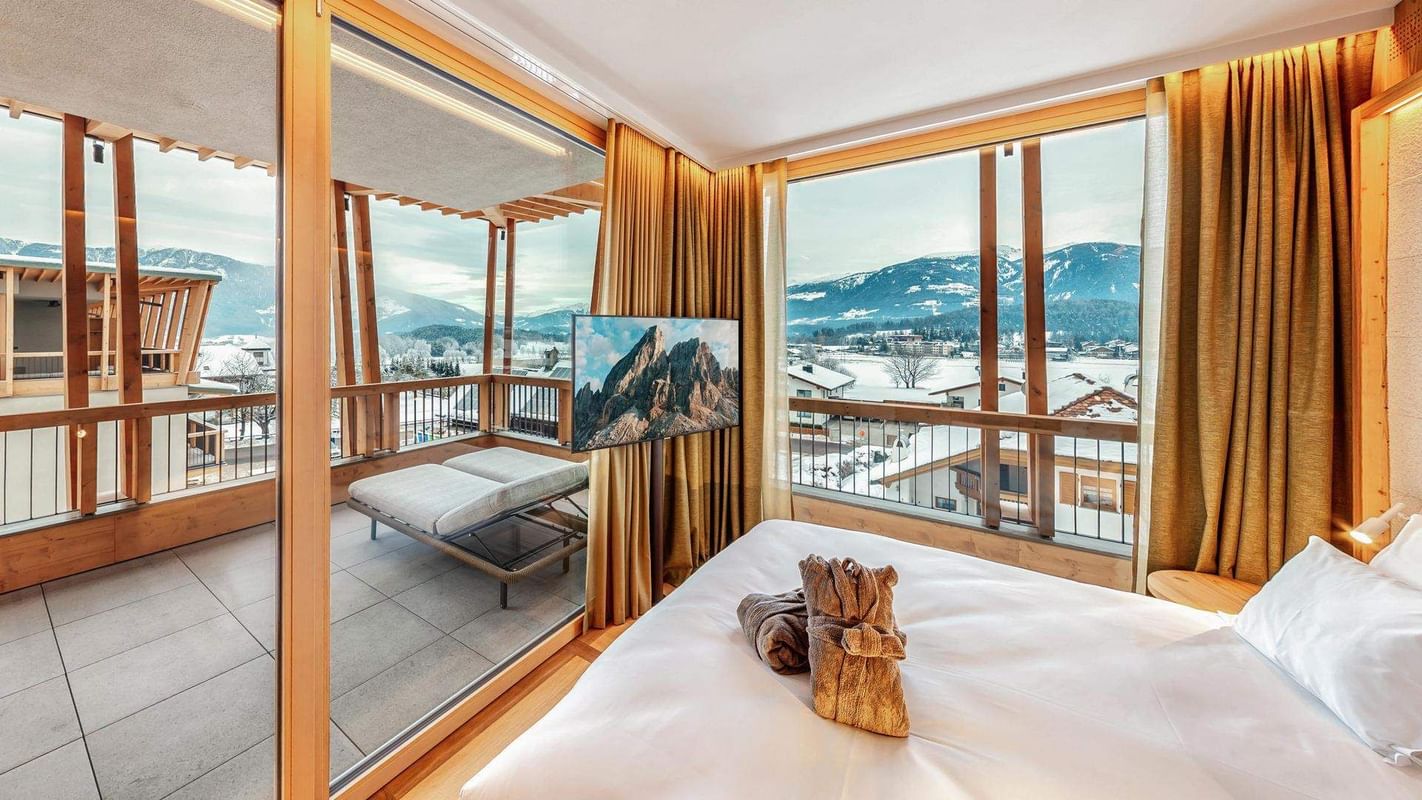 Quarto com cama, varanda e grandes janelas com vista para montanhas nevadas
