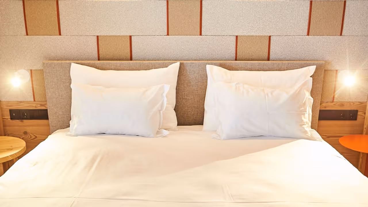 Cama branca com travesseiros e edredom no Falkensteiner Hotel Kronplatz