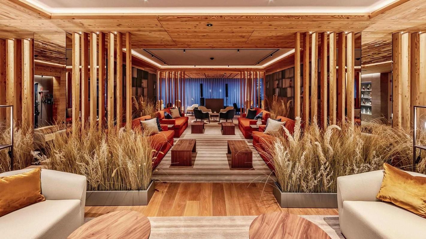 Área de lounge com vigas de madeira, sofás vermelhos e iluminação ambiente