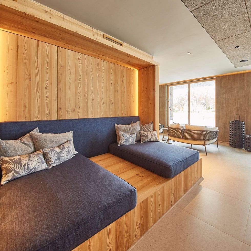 Área de lounge com madeira e assentos aconchegantes no Falkensteiner Hotel Kronplatz