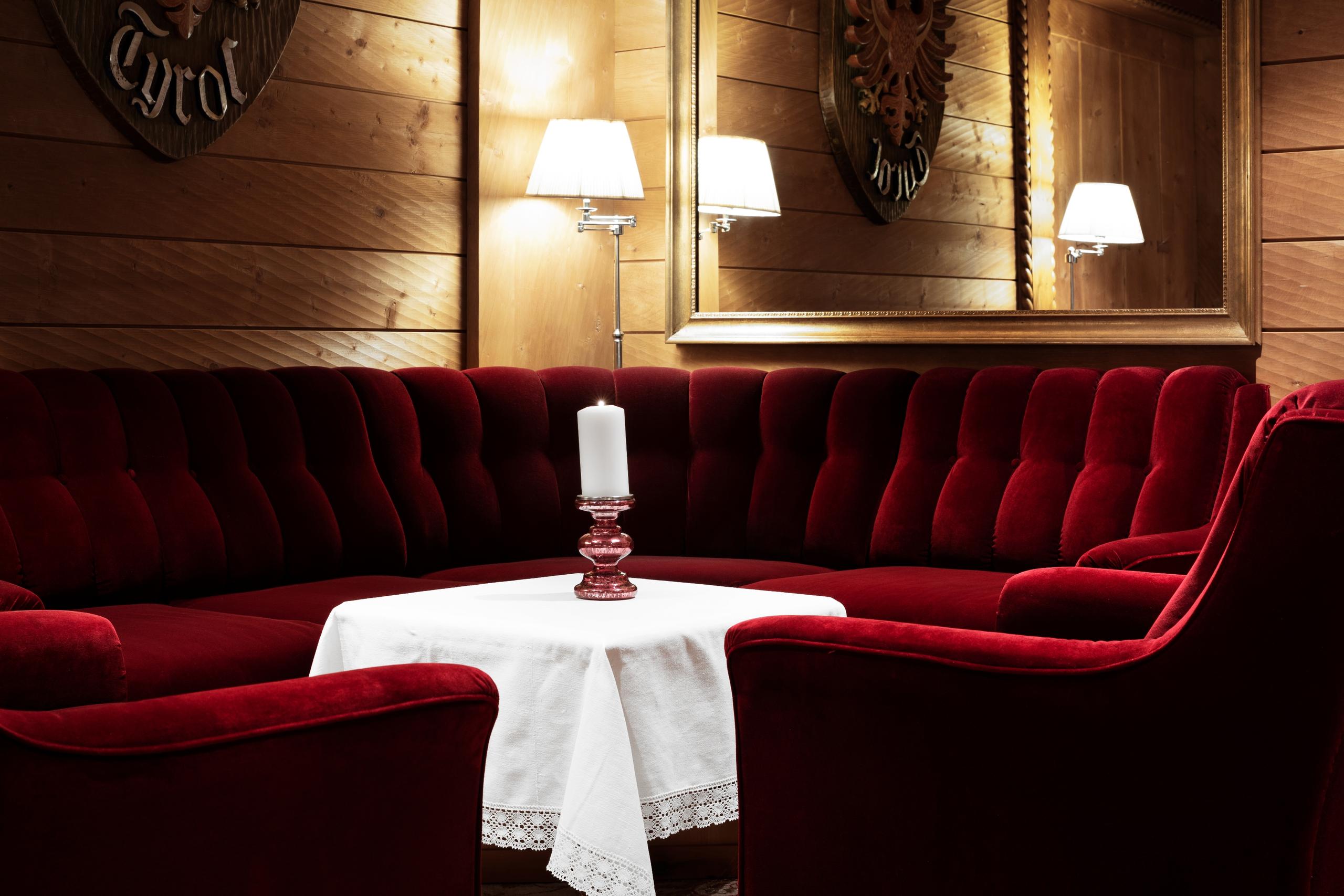 Elegante lounge com sofás de veludo vermelho no Hotel Tyrol