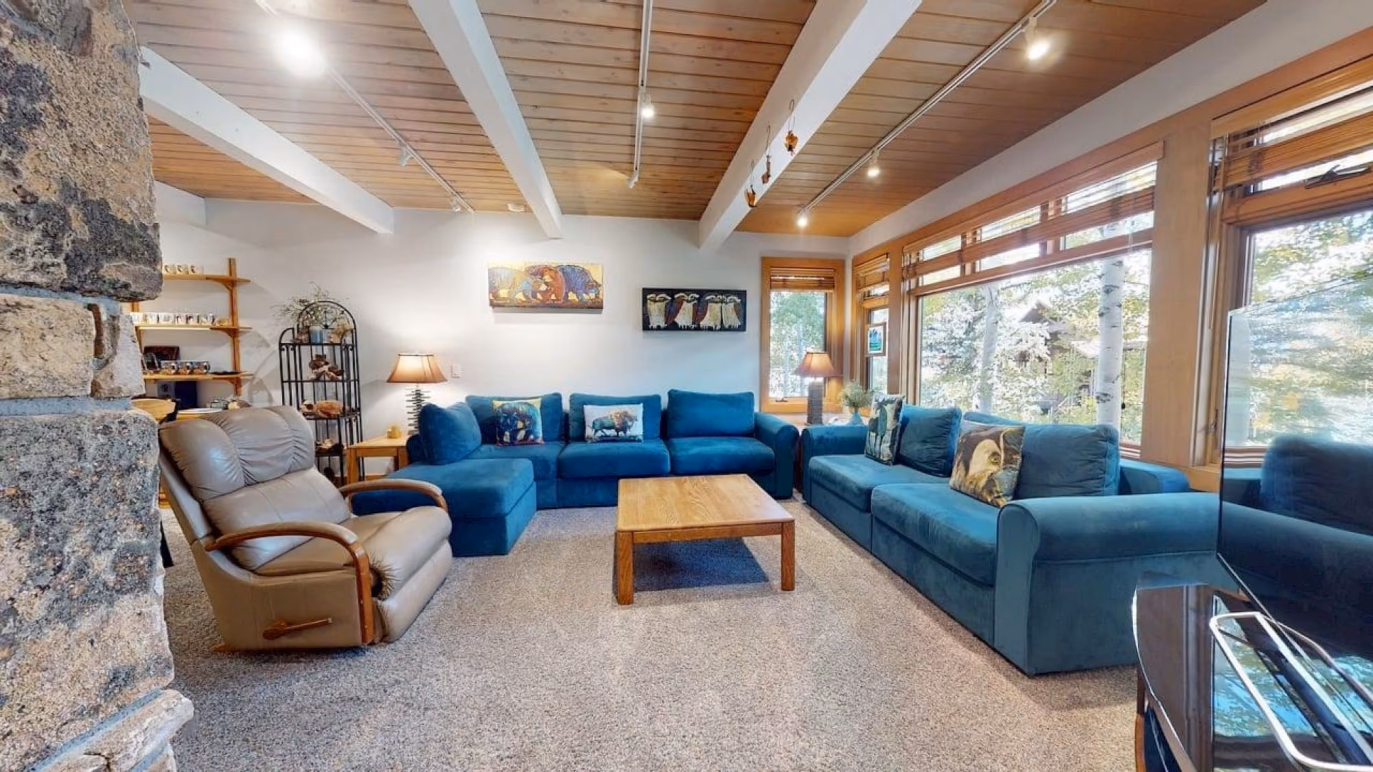 Sala de estar ampla com sofás teal e mesa de centro em madeira